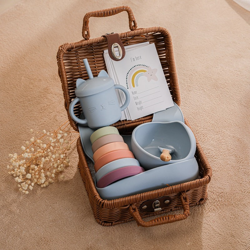 Blue bundle of silicone toys and feeding accessories for the new baby in a rattan suitcase