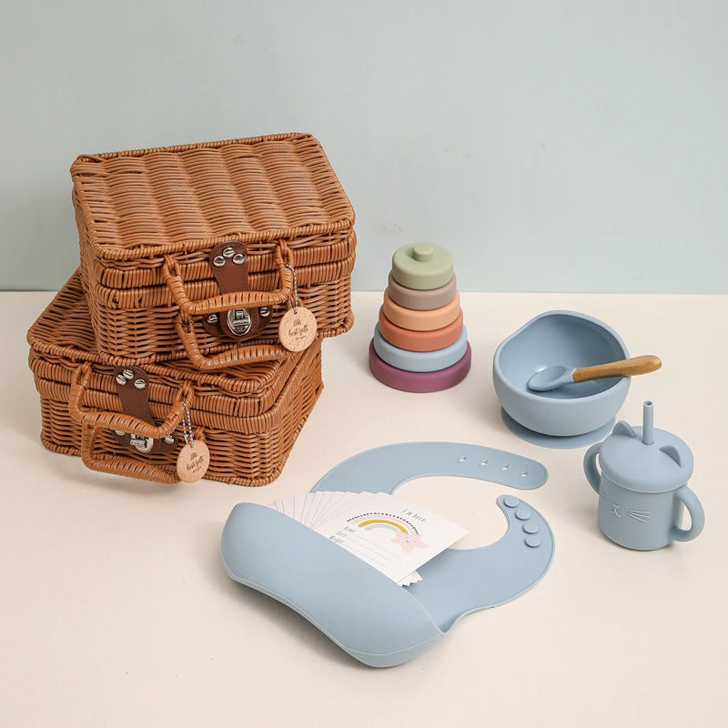 Blue bundle of silicone toys and feeding accessories for the new baby in a rattan suitcase